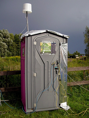 A portable toilet with network cables coming out of the door